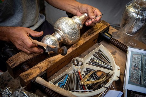 Unrecognized professional Jewellery maker working in workshop crafting silver vase. creative people