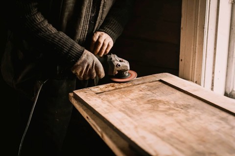 A person using a power tool to sand wood at a workbench