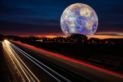 Surreal night sky with a huge moon over a town and traces of light from cars on the motorway at