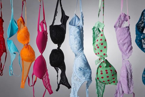 A group of colorful bras hang on a clothes line in a studio environment