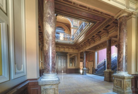 An opulent entrance hall with wood panelling, columns and a colourful ceiling painting, Villa