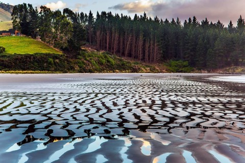 Sunrise over the ocean. Low tide. Strips of sand and water left by the ocean tide. The art of