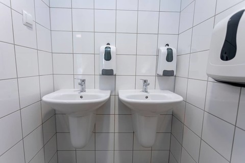 A clean and contemporary public restroom that features two modern washbasins along with convenient
