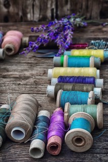Spools of thread on the old wooden background decorated with branches blossoming lavender.selective