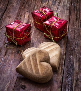 Hand-carved symbolic wooden heart on a background of yellow roses