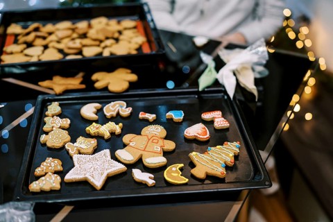 Gingerbread cookies with colorful ornaments lie on a baking sheet on the table.