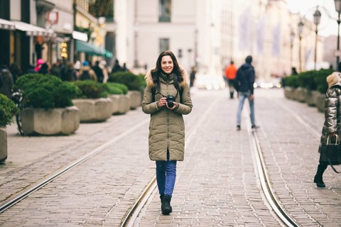 Beautiful young woman tourist with long hair stands on the background of the central street in the