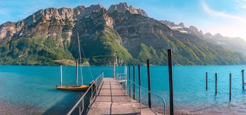 Spring landscape with a pier on the Walensee lake leading toward the Alps mountains, in