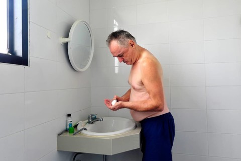 Man 60 plus shaves wet in the bathroom