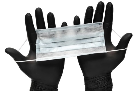 Medical man holds antivirus face mask in hands in black medical gloves. Isolated on white