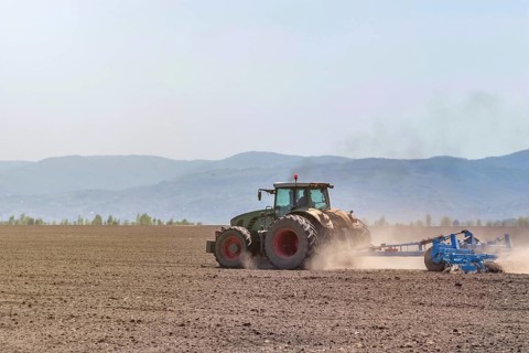 Farmer in tractor preparing land seedbed cultivator. Agriculture tractor landscape