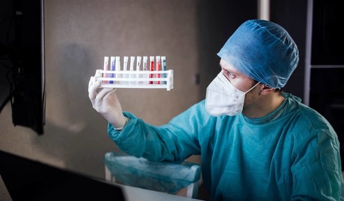 Medical professional holding a rack of test tubes under examination