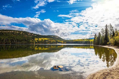 Pyramid Mountain and cumulus clouds is reflected in Pyramid Lake. Cold autumn morning in the Rocky