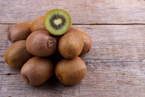 Pile of fresh kiwi on an old wooden board