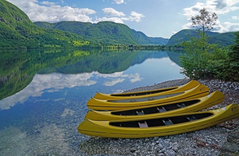 Yellow kayaks on the shore, mountain range reflected in Lake Bohinj, Triglav National Park, Julian