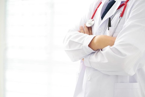 Unknow doctor posing with arms crossed in the office, he is wearing a stethoscope