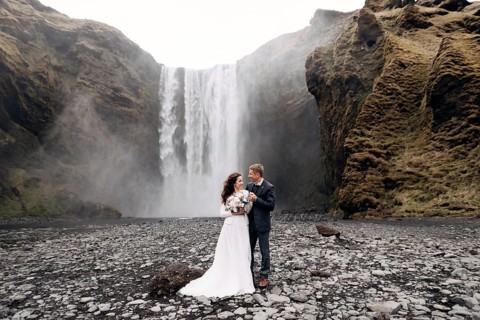 Wedding couple near Skogafoss waterfall. Destination Iceland wedding. The groom hugs the bride by