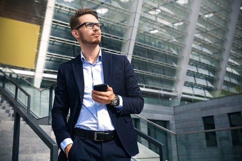 Handsome successful businessman in elegant suit outdoors walking on street in the city