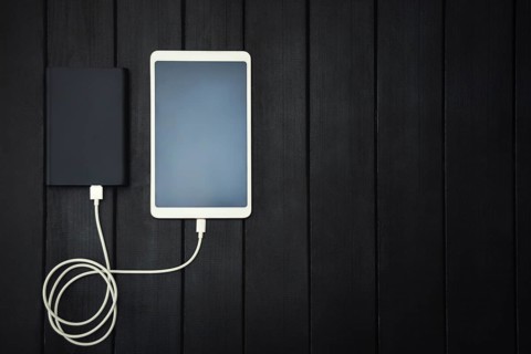 Power bank loads tablet PC, smartphone, isolated on wooden background. charging concept. free