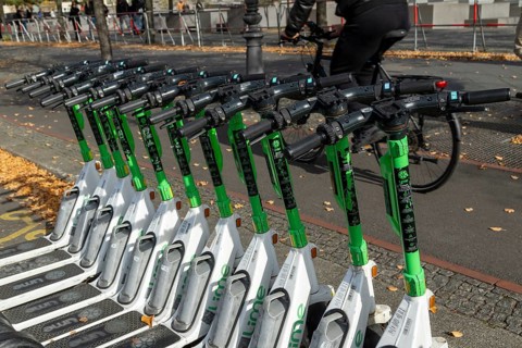 Traffic, mobility, cyclists and lined-up e-scooters from Lime in autumn on a street in Berlin,