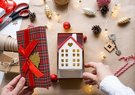 Key to house with keychain on cozy home in gift box with Christmas decor packaging. Pack present