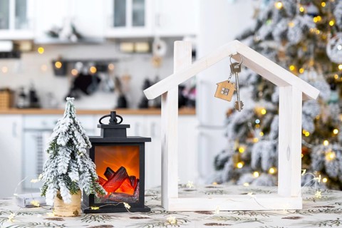 Key and tiny house of a small size on cozy home with Christmas decor on table of festive white