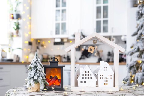 Key and tiny house of a small size on cozy home with Christmas decor on table of festive white