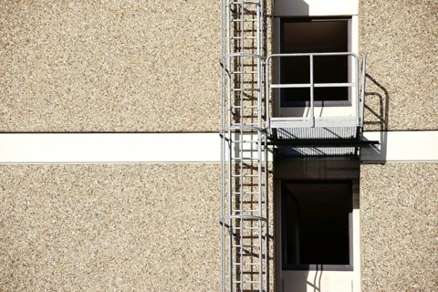 A fire escape on the side of a residential building casts a shadow