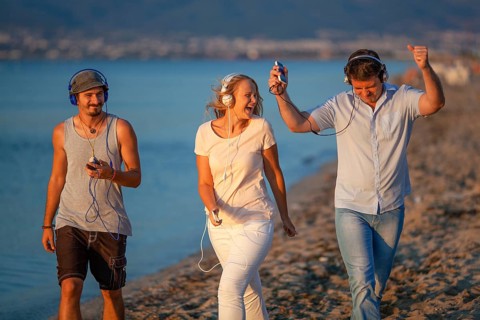 Excited friends outdoor. Young people relaxing and having fun listening to music in headphones