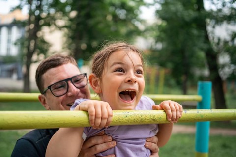 Father with child girl doing pull-ups on workout outdoor area. Healthy active lifestyle, happy