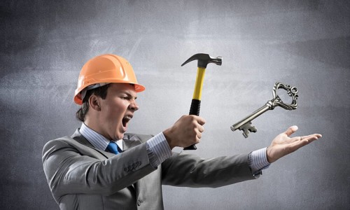 Furious businessman going to crash with hammer steel key. Young handsome contractor in business