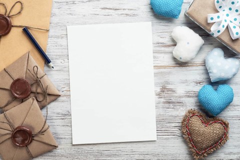 Flat lay cute composition with handmade fabric heart. White paper and retro mail envelopes on