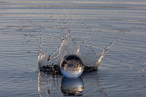 A glass sphere creates water droplets with a dynamic water crown, Mindelheim, Allgäu, Bavaria,