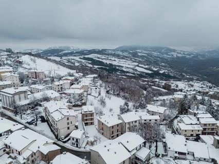 Aerial view of snow-covered houses and trees in bore, a small village nestled in the hills