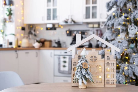 Key on Christmas tree and tiny house on cozy home with Christmas decor on table of festive white