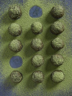 Bliss balls or energy balls sprinkled with matcha green tea. Placed in a row with some round holes