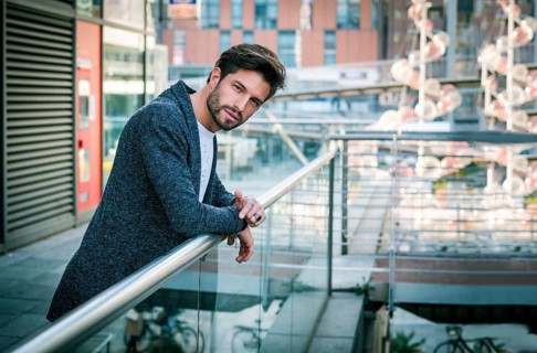 One attractive man in urban environment in city, leaning on handrail, wearing cardigan