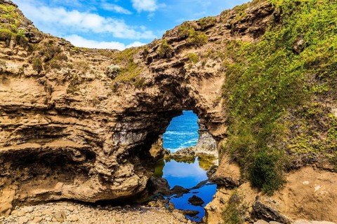 Small puddle of water in an arch. Coastal rocks formed a picturesque arch of sandstone. Great Ocean