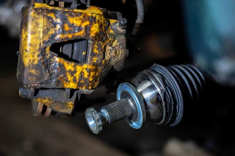 Close-up of a rusty brake caliper and mechanical components of a vehicle