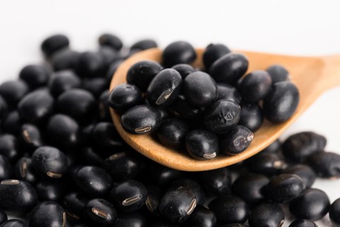 A lot of black soybeans on wooden background