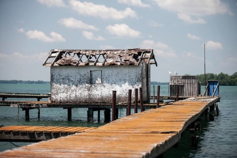 A weathered dock and shed sit along on the Detroit River along the shoreline of Southwestern