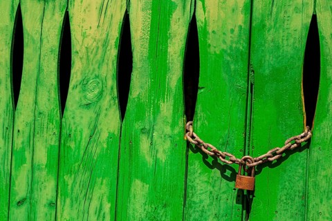Green door in the stone wall with lock locked in Cala Figuera Mallorca Spain