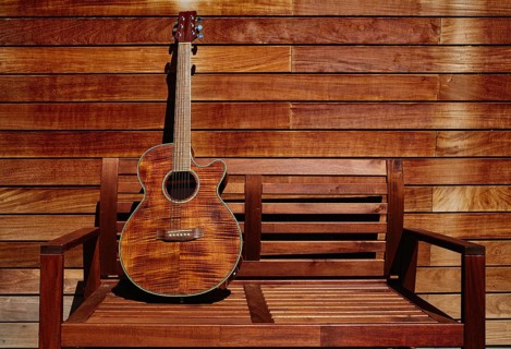 Acoustic brown guitar in a wooden stripes wooden wall monochromatic