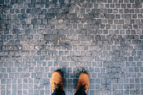 Male feet in brown boots stand on the cobblestones. Close-up.