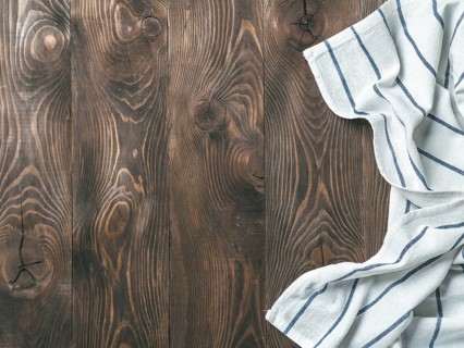 View from above on brown wooden table with linen kitchen towel or textile napkin. Blue tablecloth
