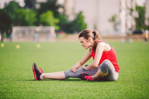 Theme sport and health. Young beautiful Caucasian woman sitting doing warm-up, warming up muscles,