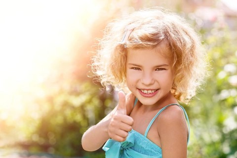Portrait of a smiling little girl showing thumbs up