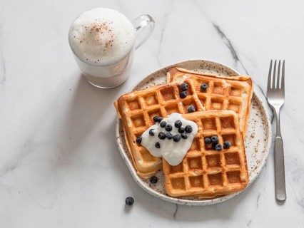 Delicious homemade baked belgian waffles with greek yogurt, blueberries and cappuccino on white