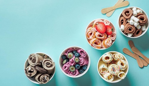 Rolled ice creams in cone cups on blue background. Different iced rolls top view or flat lay. Thai