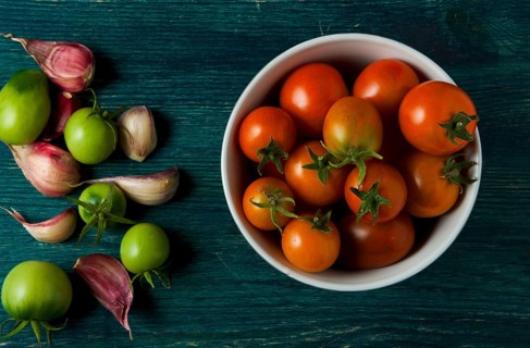Tomatoes on the background. Tomatoes, garlic on a wooden surface. View from above. Fresh vegetables